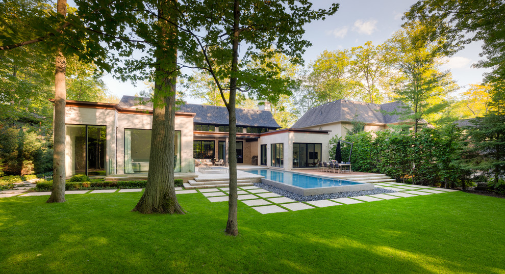 Example of a large trendy backyard stone and rectangular infinity pool fountain design