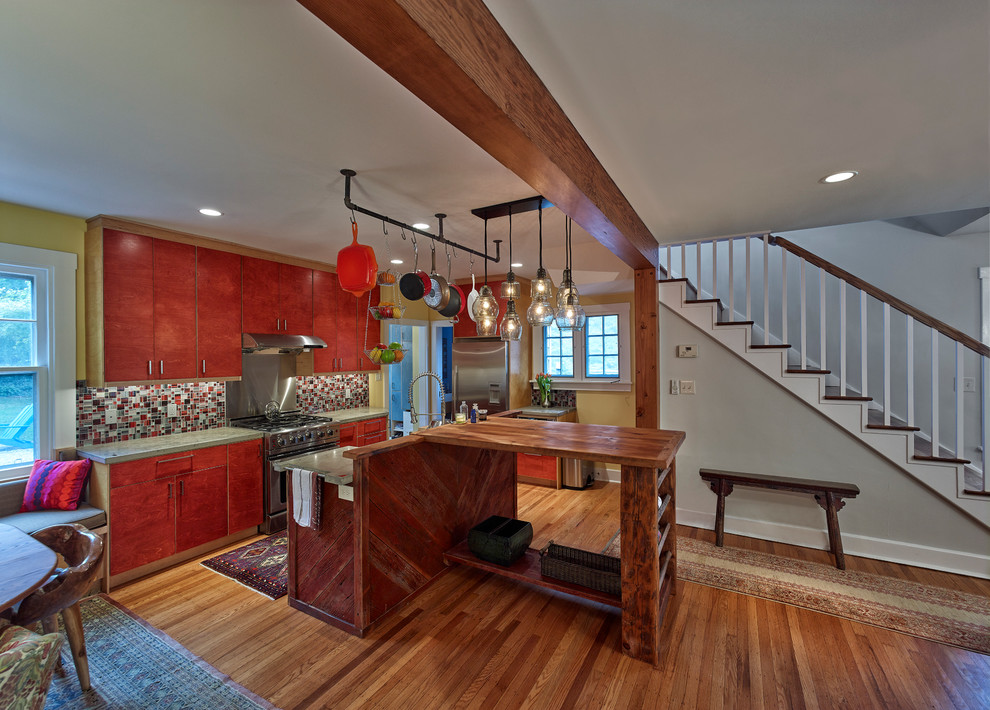 This is an example of a mid-sized country kitchen in Philadelphia with flat-panel cabinets, concrete benchtops, stainless steel appliances, light hardwood floors and with island.