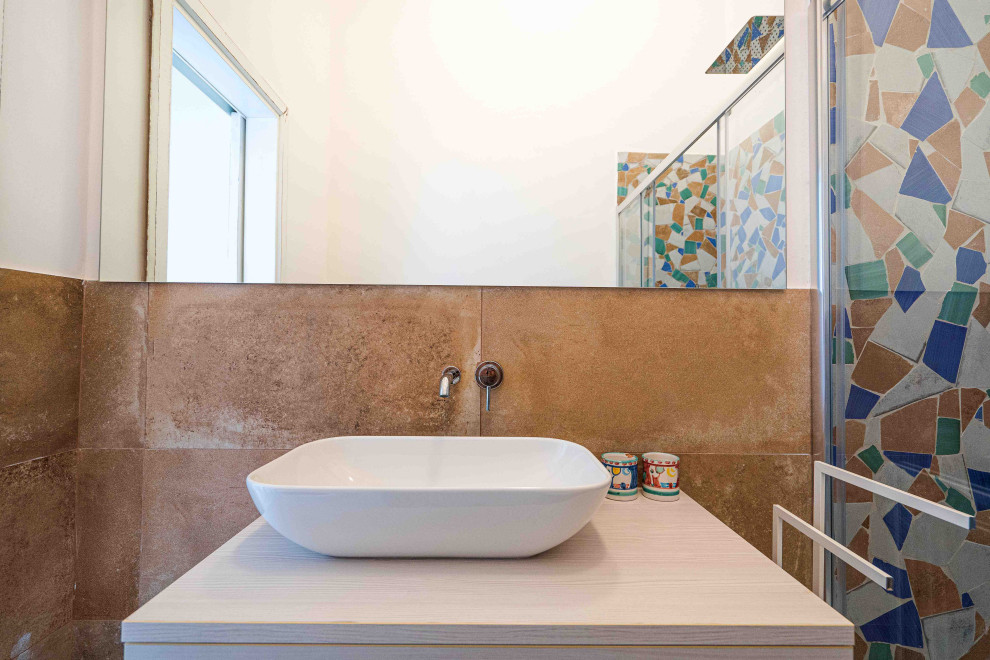 Photo of a small mediterranean 3/4 bathroom in Naples with flat-panel cabinets, light wood cabinets, a curbless shower, a two-piece toilet, multi-coloured tile, mosaic tile, white walls, porcelain floors, a vessel sink, wood benchtops, turquoise floor, a sliding shower screen, white benchtops, a single vanity and a floating vanity.