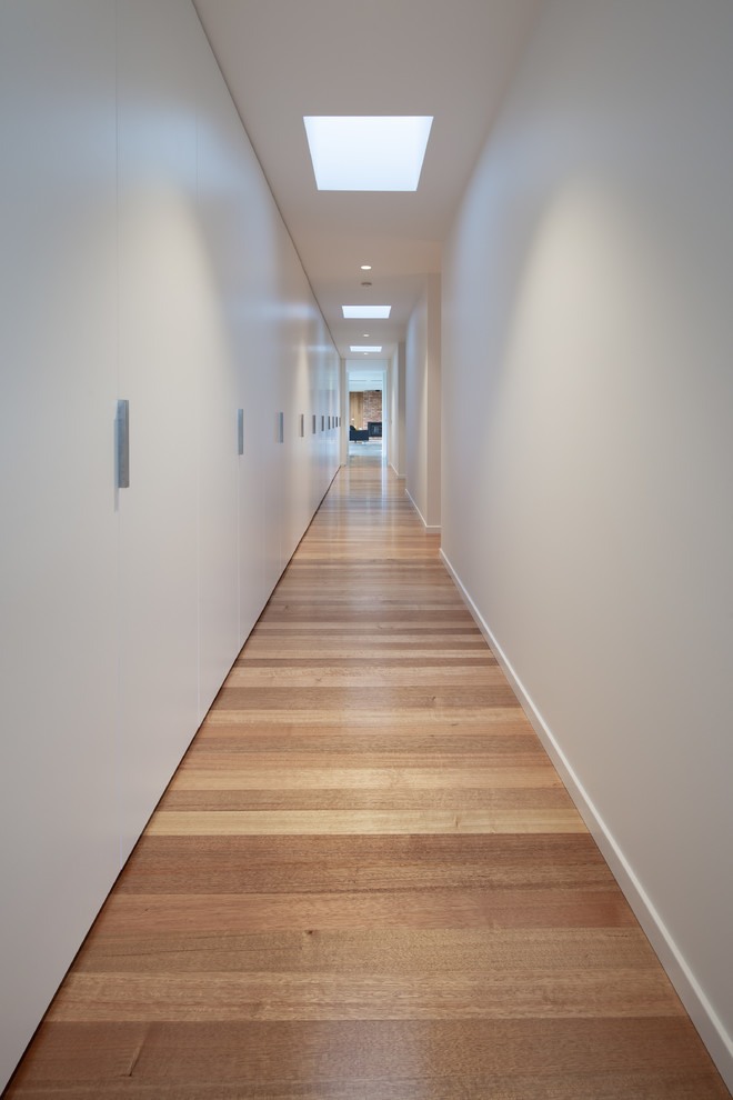 This is an example of a mid-sized country hallway in Hobart with white walls, light hardwood floors and beige floor.