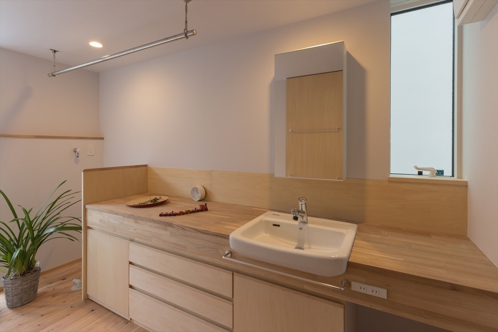 他の地域にあるトラディショナルスタイルのおしゃれなトイレ・洗面所 (フラットパネル扉のキャビネット、ベージュのタイル、白い壁、淡色無垢フローリング、ベッセル式洗面器、木製洗面台、ベージュの床) の写真