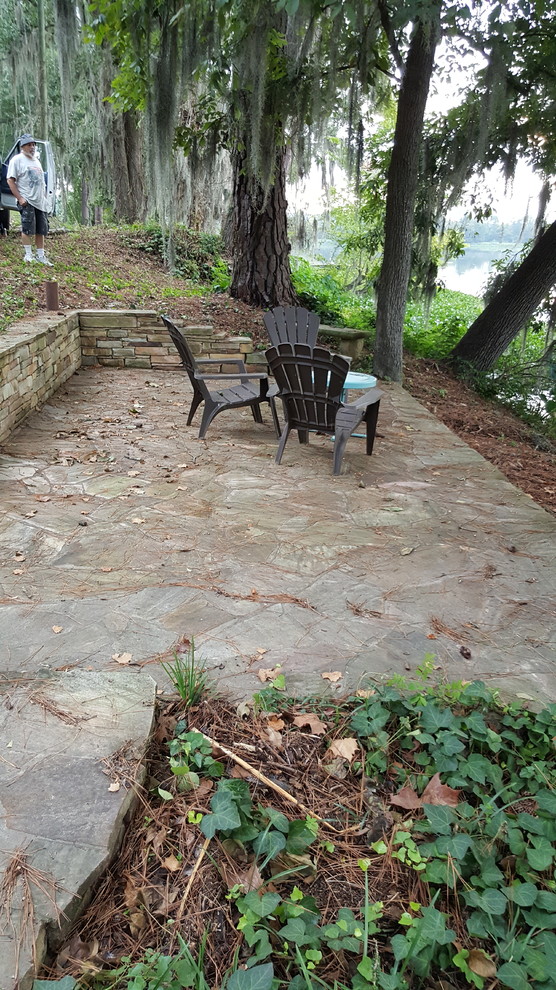 This is an example of a mid-sized traditional backyard patio in Atlanta with natural stone pavers and no cover.