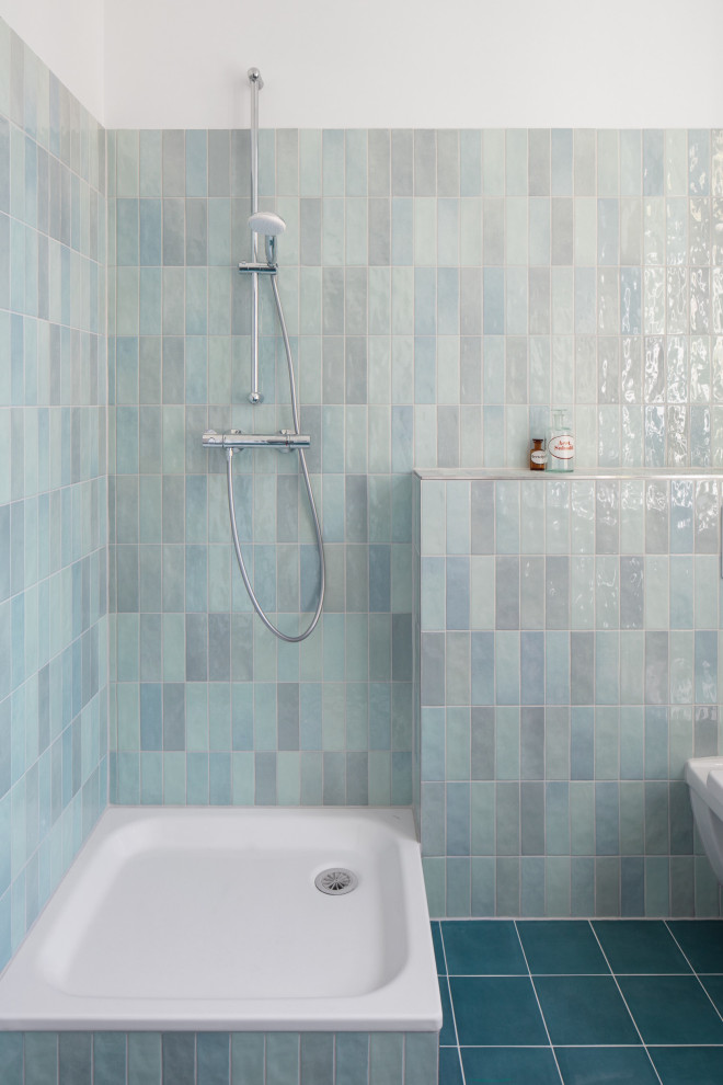 Idéer för att renovera ett mellanstort funkis badrum med dusch, med en dusch/badkar-kombination, en toalettstol med separat cisternkåpa, blå kakel, keramikplattor, blå väggar, cementgolv, ett väggmonterat handfat, blått golv och med dusch som är öppen