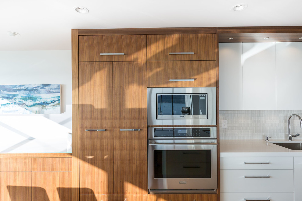 Mid-sized transitional galley medium tone wood floor open concept kitchen photo in Vancouver with an undermount sink, flat-panel cabinets, medium tone wood cabinets, quartz countertops, white backsplash, ceramic backsplash, stainless steel appliances and an island