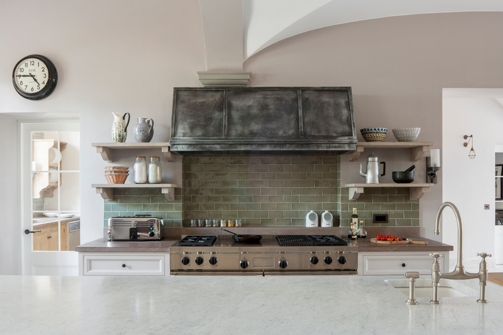 Large industrial u-shaped eat-in kitchen in London with green splashback, subway tile splashback, stainless steel appliances, light wood cabinets, marble benchtops, multiple islands and an undermount sink.
