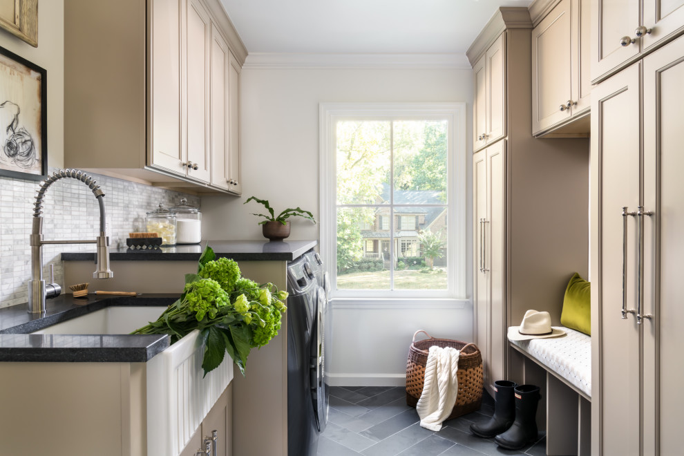 Small traditional galley dedicated laundry room in Charlotte with a farmhouse sink, beaded inset cabinets, beige cabinets, granite benchtops, grey splashback, marble splashback, white walls, slate floors, a side-by-side washer and dryer, black floor and black benchtop.