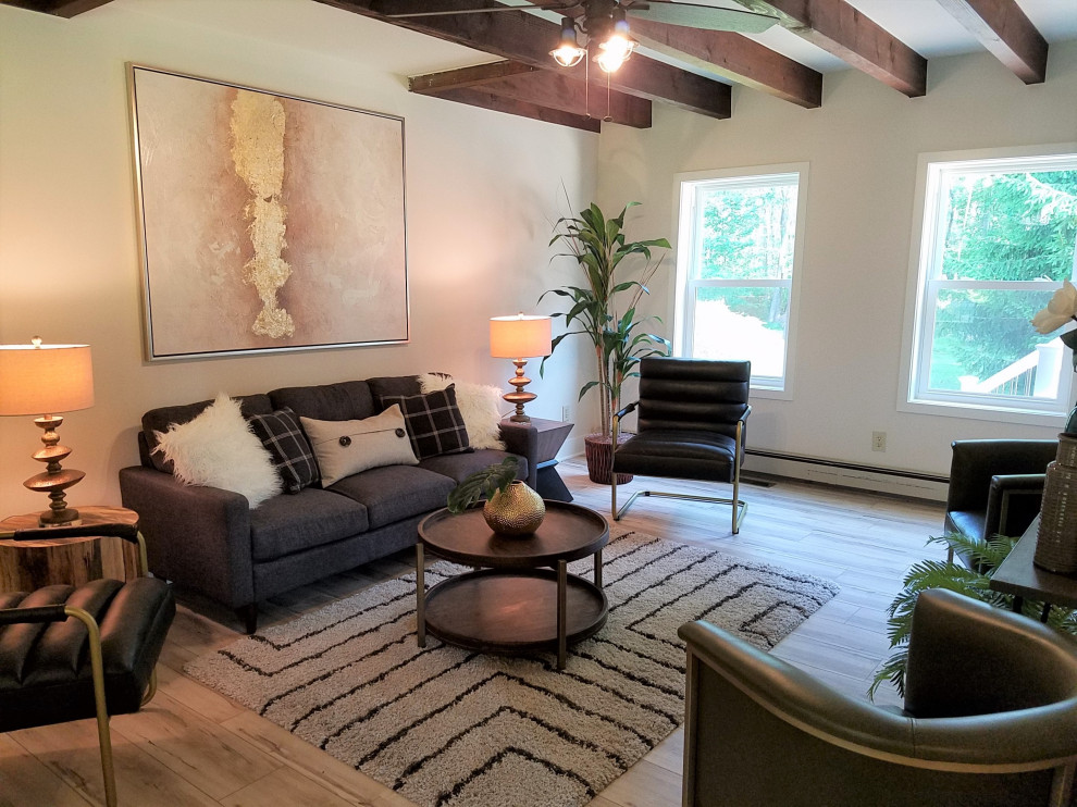 Photo of a small eclectic enclosed living room in Philadelphia with white walls, laminate floors, grey floor and exposed beam.