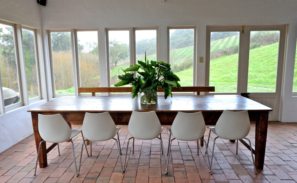 This is an example of a country dining room in Adelaide with brick floors.