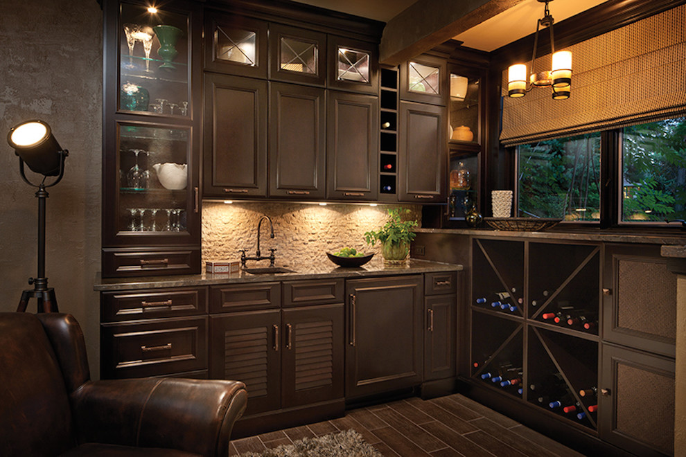 Inspiration for a mid-sized traditional l-shaped wet bar in Orange County with an undermount sink, recessed-panel cabinets, dark wood cabinets, granite benchtops, beige splashback, stone tile splashback and dark hardwood floors.