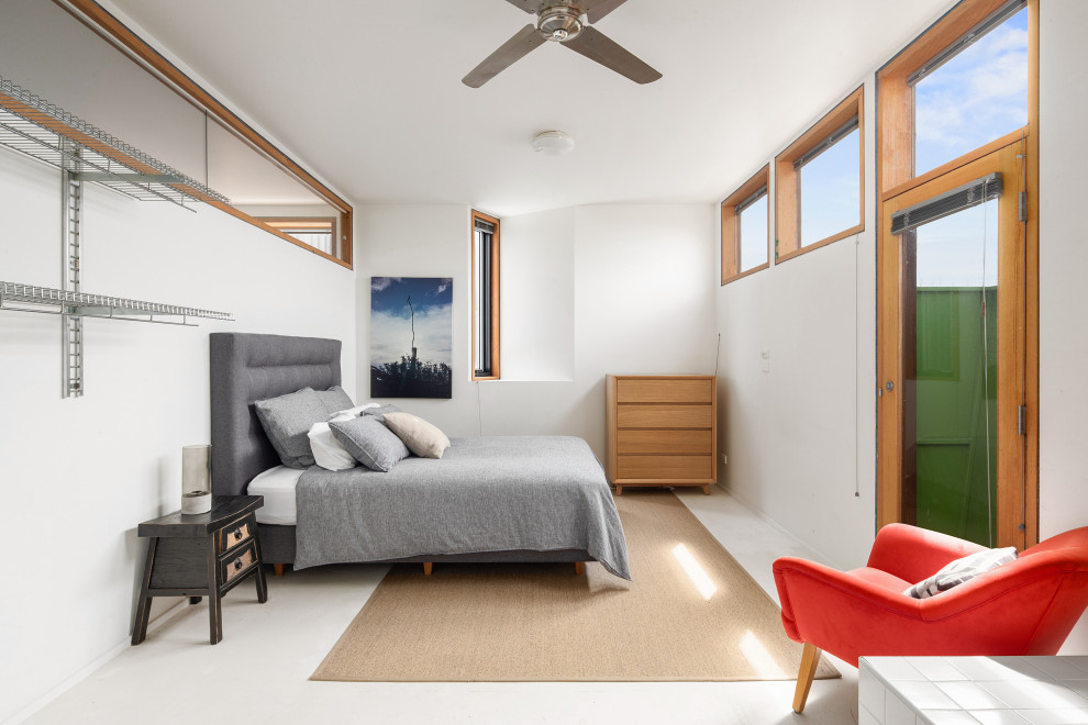 Photo of a mid-sized beach style master bedroom in Other with white walls and concrete floors.