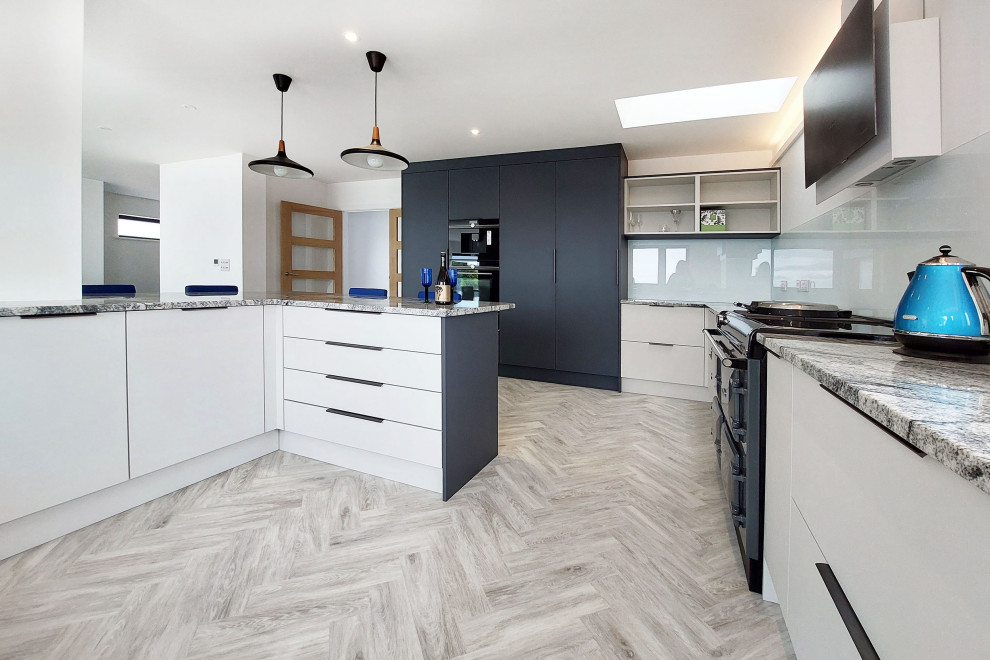 Medium sized contemporary grey and white u-shaped open plan kitchen in Cambridgeshire with flat-panel cabinets, grey cabinets, quartz worktops and feature lighting.