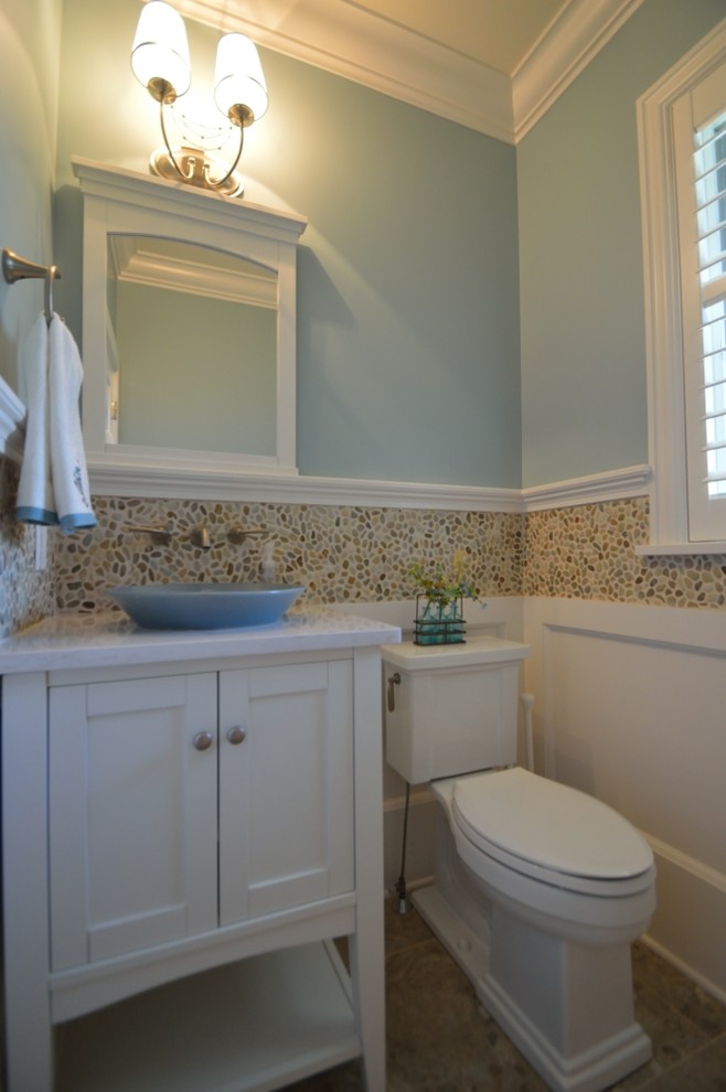 Photo of a traditional powder room in New York with a vessel sink, shaker cabinets, white cabinets, engineered quartz benchtops, a two-piece toilet, multi-coloured tile, pebble tile, blue walls and porcelain floors.