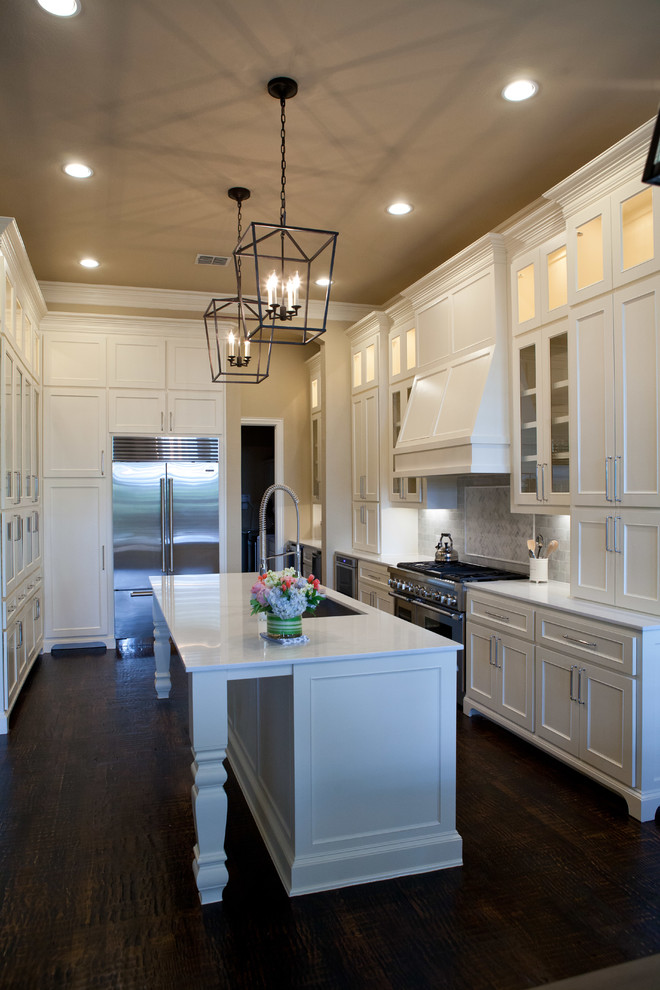 Inspiration for a large transitional u-shaped dark wood floor open concept kitchen remodel in Dallas with an undermount sink, glass-front cabinets, white cabinets, quartz countertops, white backsplash, stone tile backsplash, stainless steel appliances and an island