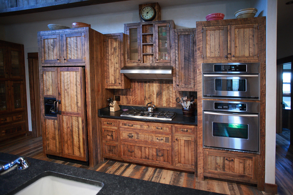 Inspiration for a rustic medium tone wood floor kitchen remodel with an undermount sink, shaker cabinets, distressed cabinets, granite countertops, stainless steel appliances and an island