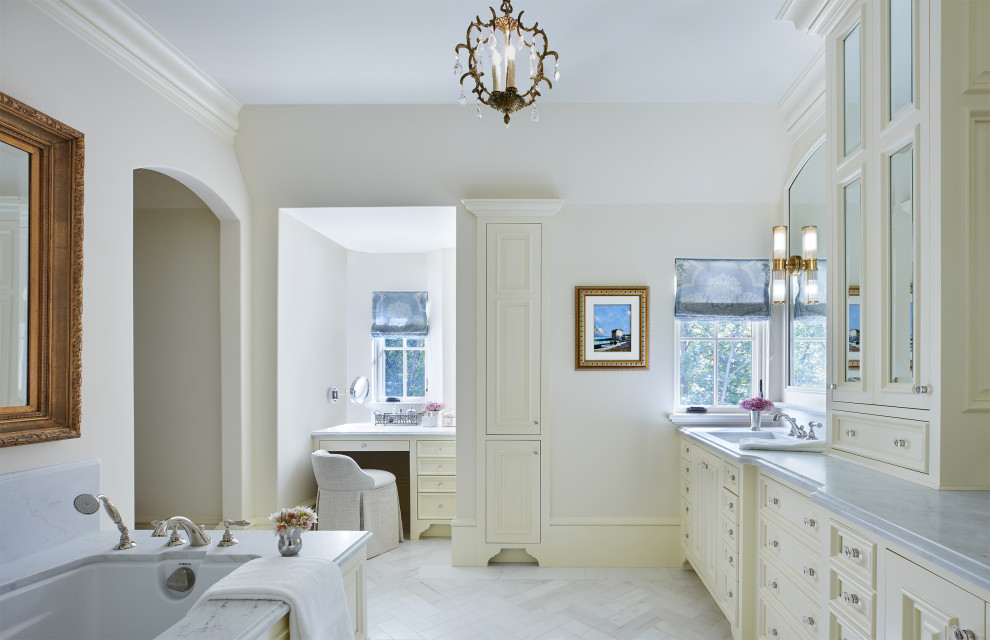 Inspiration for a mid-sized master bathroom in Minneapolis with recessed-panel cabinets, white cabinets, a drop-in tub, white tile, marble, white walls, marble floors, an integrated sink, marble benchtops, white floor, white benchtops, a double vanity and a built-in vanity.
