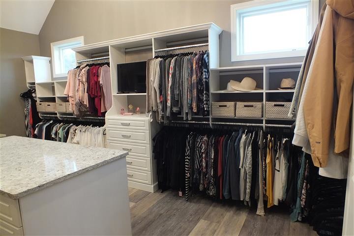 Photo of an expansive contemporary gender-neutral walk-in wardrobe in Cleveland with raised-panel cabinets, white cabinets, vinyl floors and brown floor.