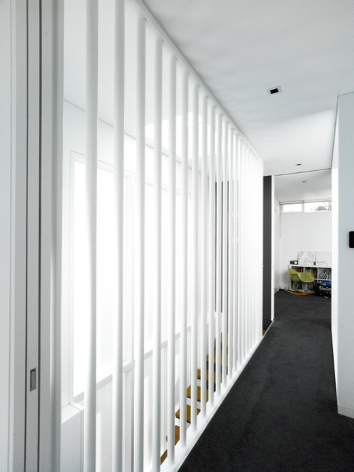 This is an example of a mid-sized contemporary hallway in Sydney with white walls, carpet and black floor.