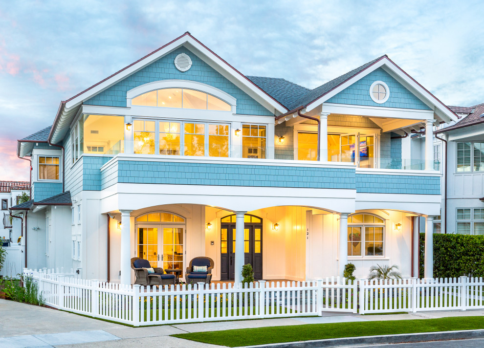 Foto della villa blu stile marinaro a due piani di medie dimensioni con rivestimento con lastre in cemento, tetto a capanna, copertura a scandole, tetto nero e pannelli e listelle di legno