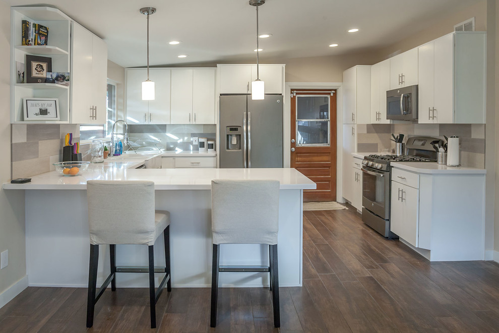 Transitional u-shaped porcelain tile open concept kitchen photo in Phoenix with a farmhouse sink, shaker cabinets, white cabinets, quartz countertops, multicolored backsplash, porcelain backsplash, stainless steel appliances and an island
