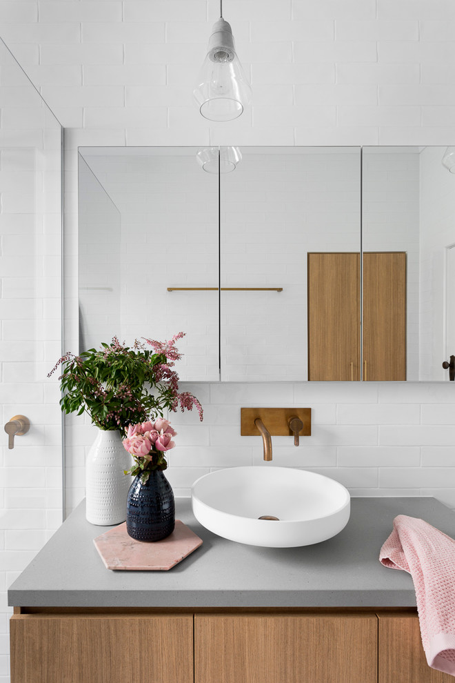 Large contemporary master bathroom in Melbourne with flat-panel cabinets, medium wood cabinets, a freestanding tub, an open shower, a two-piece toilet, gray tile, white tile, subway tile, grey walls, ceramic floors, a vessel sink, concrete benchtops, blue floor, an open shower and grey benchtops.