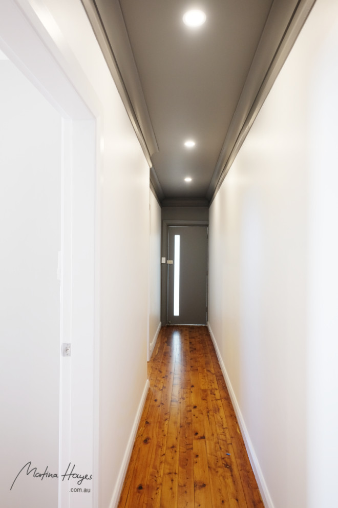 シドニーにあるラグジュアリーな中くらいなコンテンポラリースタイルのおしゃれな廊下 (白い壁、無垢フローリング、茶色い床、クロスの天井) の写真