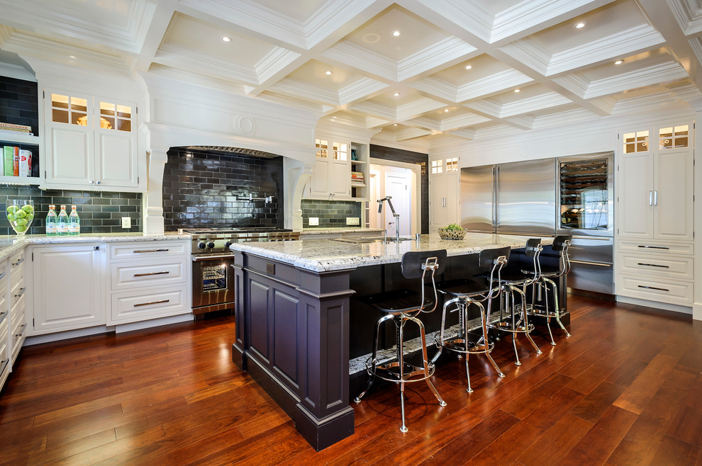 This is an example of a large traditional l-shaped kitchen in San Francisco with raised-panel cabinets, stainless steel appliances, subway tile splashback, white cabinets, granite benchtops, grey splashback, medium hardwood floors, with island and brown floor.