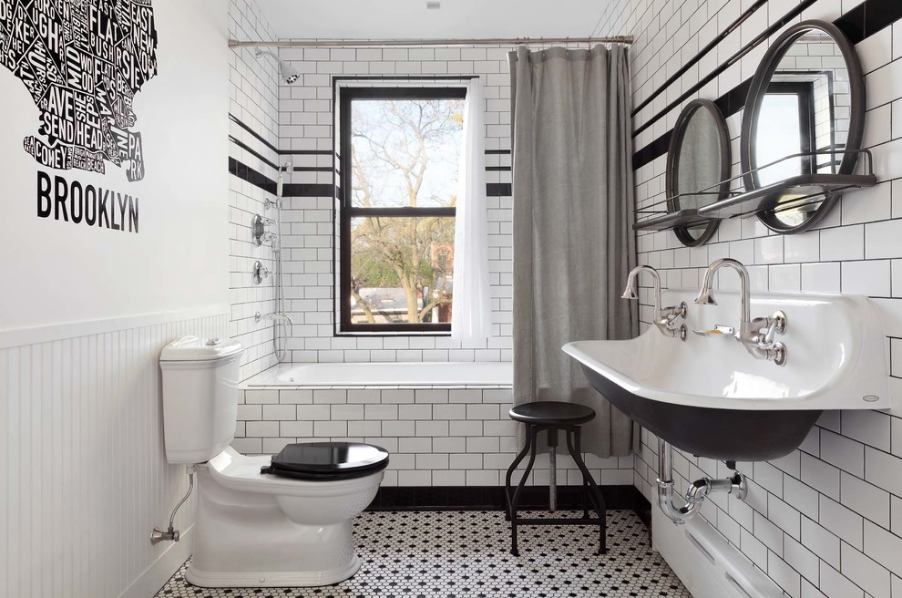 This is an example of a mid-sized industrial master bathroom in New York with a drop-in tub, a shower/bathtub combo, a two-piece toilet, white tile, subway tile, white walls, mosaic tile floors, a trough sink, white floor and a shower curtain.