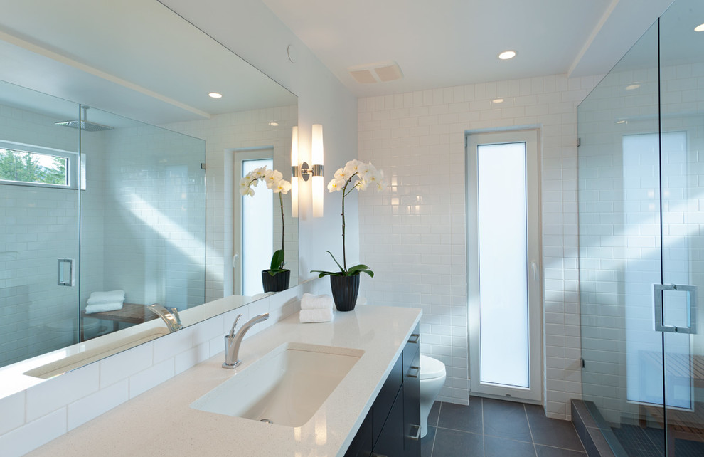 Photo of a mid-sized contemporary master bathroom in Vancouver with an undermount sink, flat-panel cabinets, dark wood cabinets, engineered quartz benchtops, an alcove shower, a one-piece toilet, white tile, ceramic tile, white walls and porcelain floors.