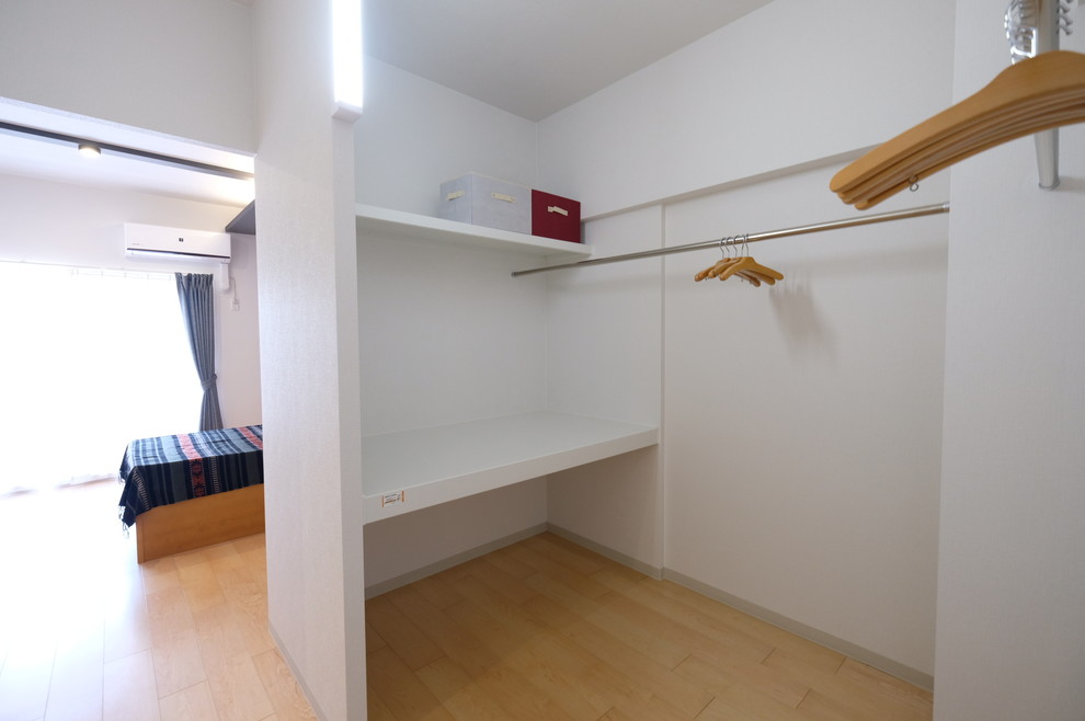 Modern inredning av ett litet walk-in-closet för könsneutrala, med öppna hyllor, vita skåp, plywoodgolv och beiget golv