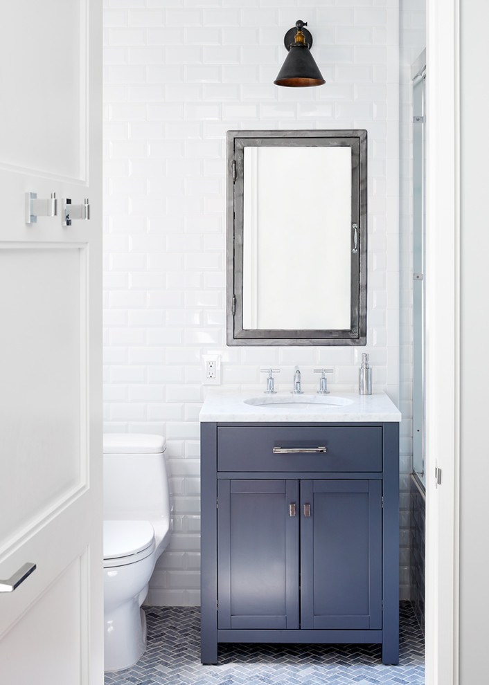 Inspiration for a mid-sized contemporary 3/4 bathroom in New York with shaker cabinets, blue cabinets, an alcove tub, a shower/bathtub combo, a two-piece toilet, white tile, subway tile, white walls, mosaic tile floors, an undermount sink, quartzite benchtops, grey floor and a sliding shower screen.