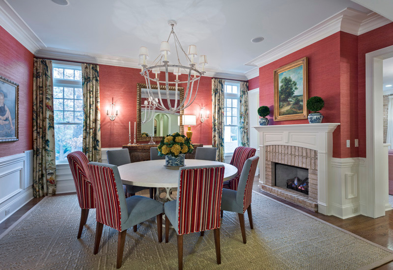 Large traditional separate dining room in Charlotte with red walls, medium hardwood floors, a standard fireplace and a brick fireplace surround.