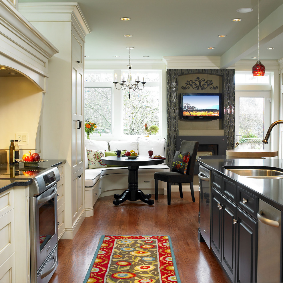 This is an example of a traditional eat-in kitchen in Vancouver with white cabinets and stainless steel appliances.