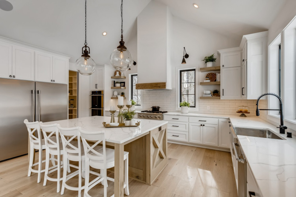 Design ideas for a large modern u-shaped kitchen/diner in Minneapolis with a belfast sink, shaker cabinets, white cabinets, engineered stone countertops, white splashback, ceramic splashback, stainless steel appliances, light hardwood flooring, an island, white worktops and exposed beams.
