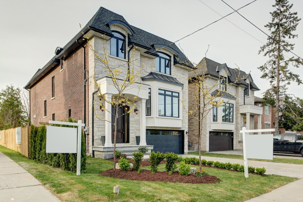 This is an example of a mid-sized transitional two-storey beige exterior in Toronto with stone veneer and a hip roof.