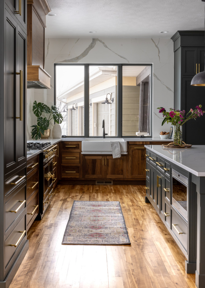 Inspiration for a mid-sized transitional l-shaped light wood floor and brown floor eat-in kitchen remodel with a farmhouse sink, shaker cabinets, blue cabinets, quartz countertops, white backsplash, quartz backsplash, black appliances, an island and white countertops