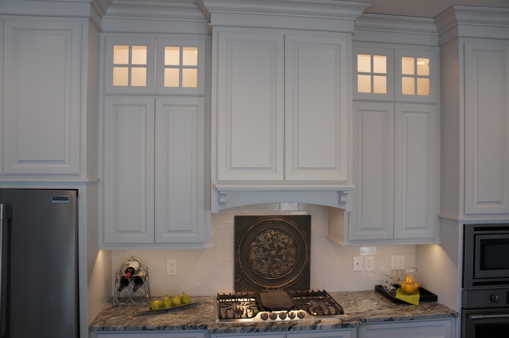 Inspiration for a transitional single-wall dark wood floor open concept kitchen remodel with a farmhouse sink, raised-panel cabinets, white cabinets, granite countertops, white backsplash, stainless steel appliances and an island