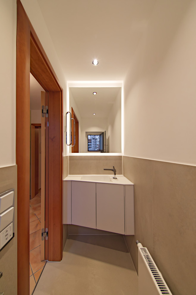 Mid-sized modern powder room in Munich with flat-panel cabinets, white cabinets, a wall-mount toilet, beige tile, stone tile, white walls, a wall-mount sink, solid surface benchtops, beige floor, white benchtops and a floating vanity.