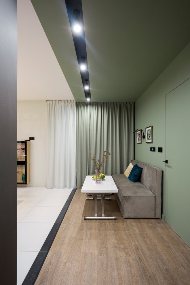 Свежая идея для дизайна: объединенная гостиная комната среднего размера в современном стиле с зелеными стенами, полом из ламината, зоной отдыха и коричневым полом без камина - отличное фото интерьера