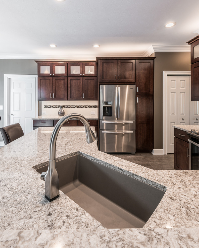 Inspiration for a mid-sized transitional u-shaped vinyl floor and brown floor kitchen remodel with an undermount sink, recessed-panel cabinets, brown cabinets, quartz countertops, multicolored backsplash, porcelain backsplash, stainless steel appliances, a peninsula and multicolored countertops
