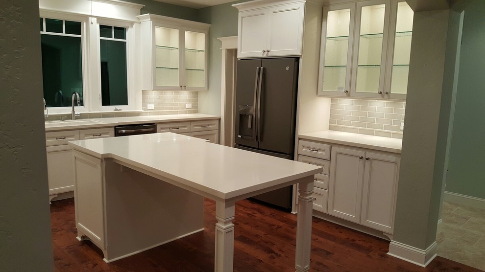 Mid-sized transitional u-shaped dark wood floor and brown floor enclosed kitchen photo in Austin with an undermount sink, recessed-panel cabinets, white cabinets, gray backsplash, porcelain backsplash, stainless steel appliances, an island, quartz countertops and white countertops