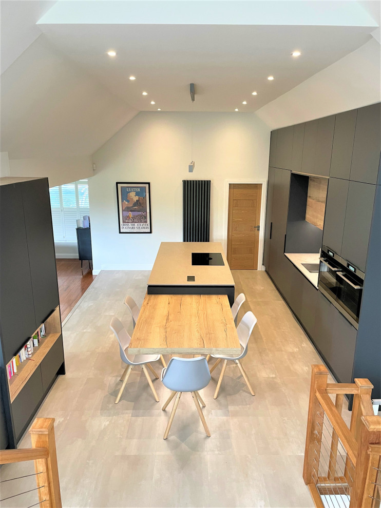 Photo of a large contemporary single-wall open plan kitchen in Other with a double-bowl sink, flat-panel cabinets, light wood cabinets, solid surface benchtops, grey splashback, black appliances, vinyl floors, with island, grey floor, grey benchtop and vaulted.