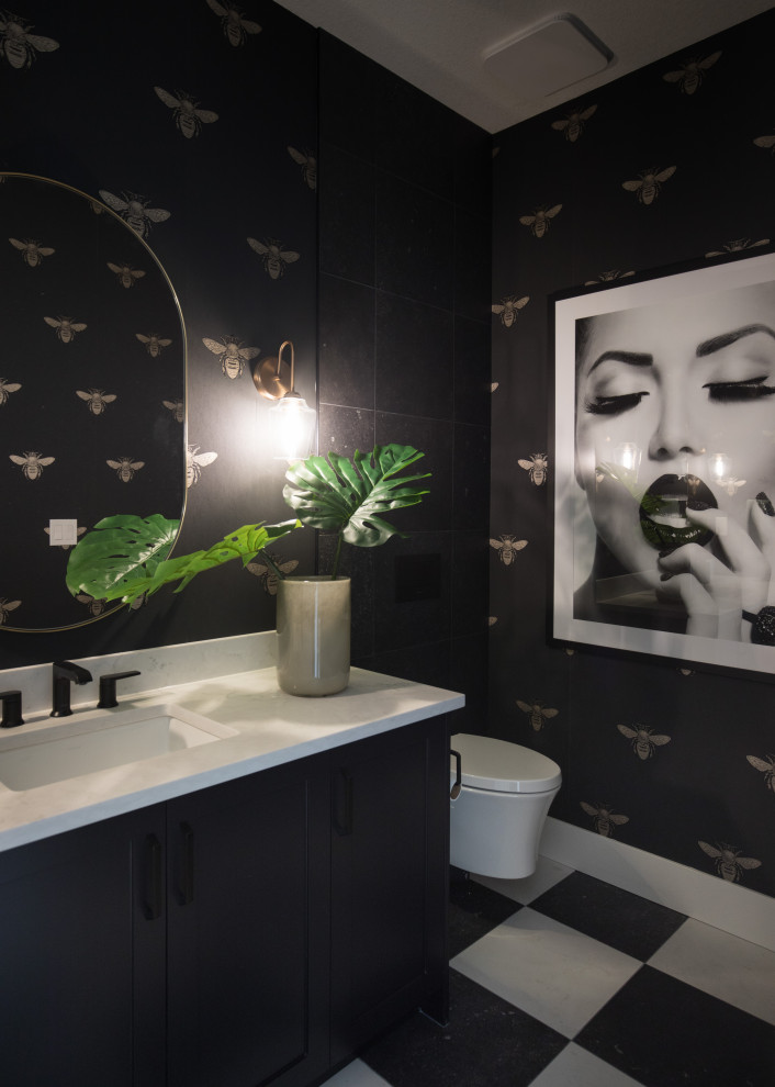 Large contemporary powder room in Calgary with shaker cabinets, black cabinets, a wall-mount toilet, black tile, porcelain tile, black walls, porcelain floors, an undermount sink, engineered quartz benchtops, black floor, white benchtops, a built-in vanity and wallpaper.