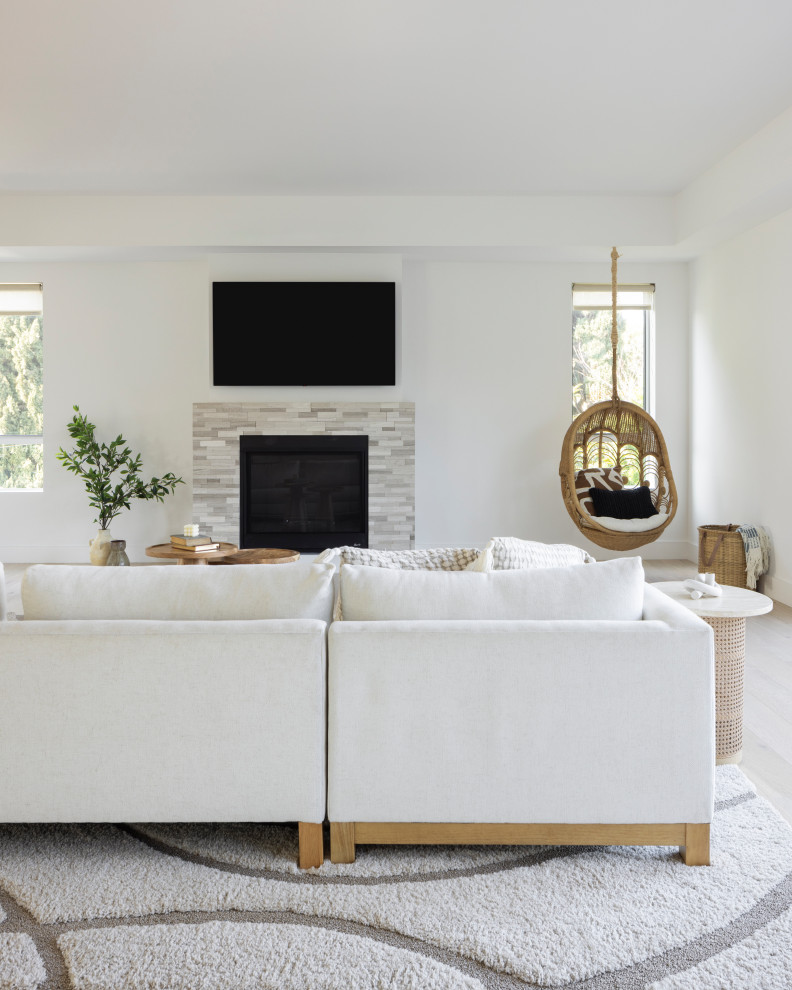 Photo of a large beach style mezzanine living room in Los Angeles with white walls, a standard fireplace, a wall mounted tv and brown floors.