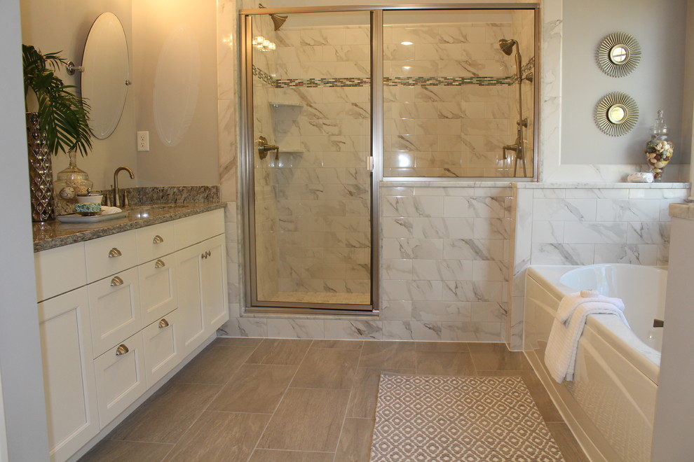 This is an example of a large transitional master bathroom in Boston with shaker cabinets, white cabinets, an alcove tub, an alcove shower, a one-piece toilet, gray tile, porcelain tile, grey walls, porcelain floors, an undermount sink and granite benchtops.