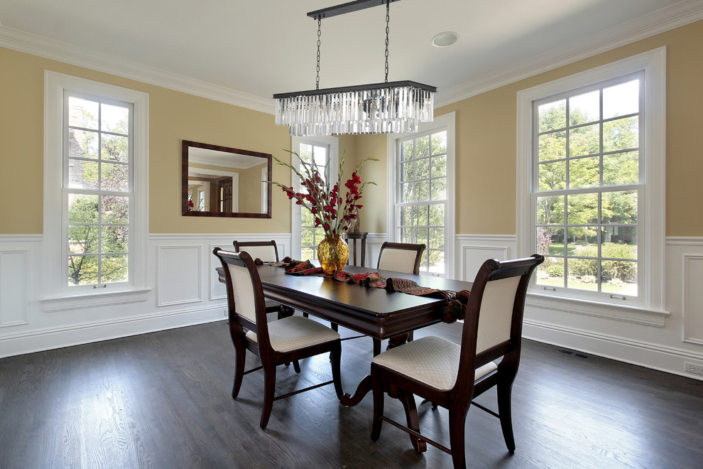 Design ideas for an expansive traditional separate dining room in New York with yellow walls, dark hardwood floors, no fireplace and brown floor.