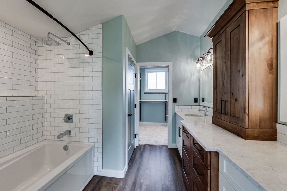 Cette photo montre une salle de bain craftsman avec un placard avec porte à panneau encastré, des portes de placard blanches, une baignoire posée, un combiné douche/baignoire, WC séparés, un carrelage blanc, des carreaux de béton, un mur bleu, un sol en vinyl, un lavabo encastré, un plan de toilette en quartz, un sol marron, une cabine de douche avec un rideau, un plan de toilette blanc, meuble simple vasque et meuble-lavabo encastré.