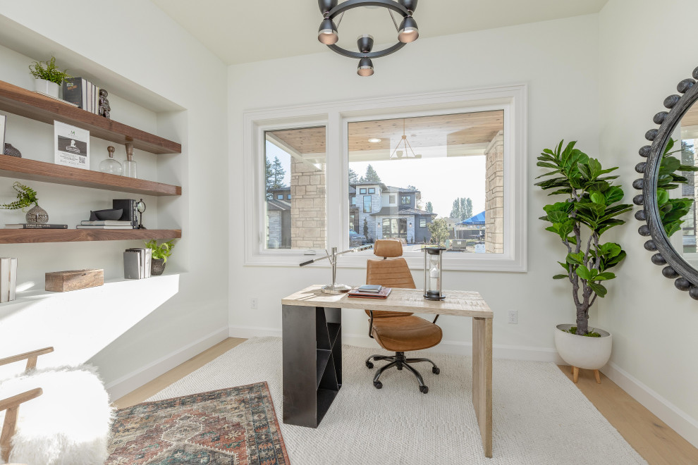 Mittelgroßes Mediterranes Arbeitszimmer mit Arbeitsplatz, weißer Wandfarbe, hellem Holzboden, freistehendem Schreibtisch und braunem Boden in Portland