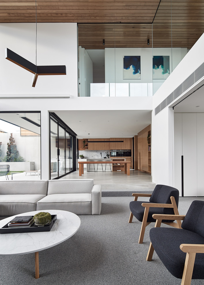This is an example of a modern open concept family room in Melbourne with white walls, carpet and grey floor.