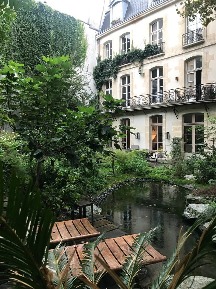 Inspiration for a traditional backyard garden in Paris with with pond and decking.