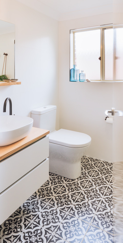 Small contemporary 3/4 bathroom in Sydney with flat-panel cabinets, white cabinets, a corner shower, a one-piece toilet, white tile, ceramic tile, white walls, ceramic floors, a vessel sink, wood benchtops, black floor and a hinged shower door.